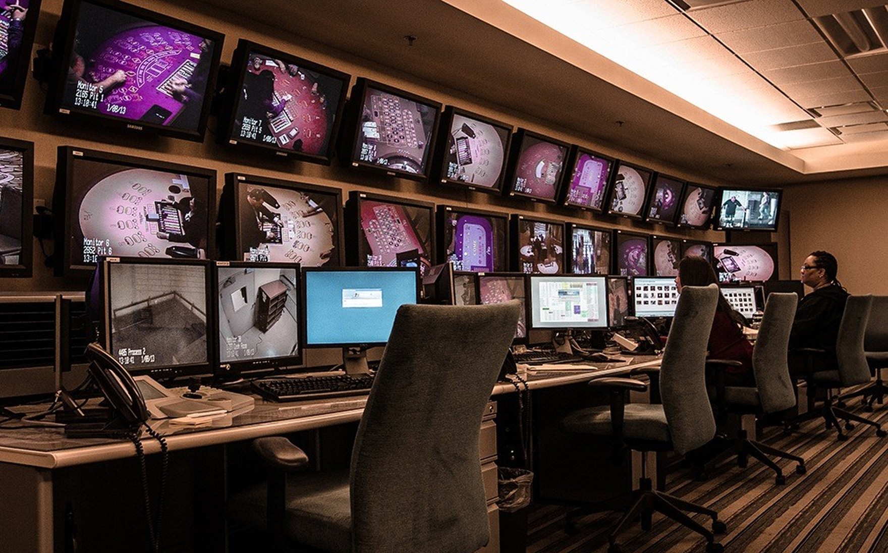 A surveillance control desk with a wall of monitors.